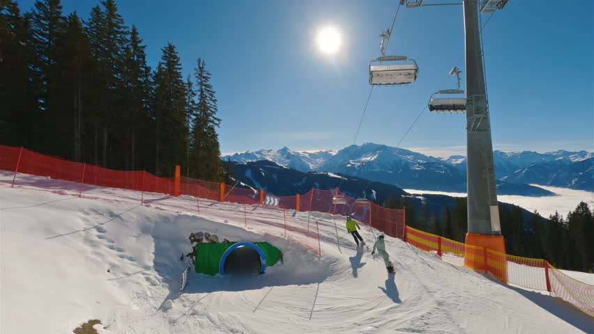 Skiing and snowboarding in Winter Fun park with ski tunnel in Alps ski resort in Austria in Zell am See