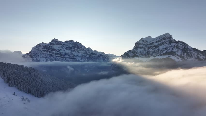 Snowy mountain peaks of Rautispitz and Glärnisch, surrounded by mist, Switzerland