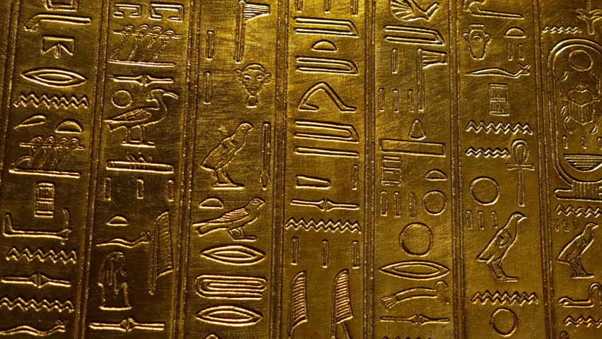 Amazing hieroglyphs carving on golden wall of tomb. Macro view of antique symbols engraved on plate, ancient Egypt.