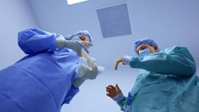 Female nurse prepares latex gloves for the doctor. Male surgeon waiting for the gloves addresses to camera. Low angle view. - Powered by Shutterstock - Get 15% off with code: PIKWIZARD15