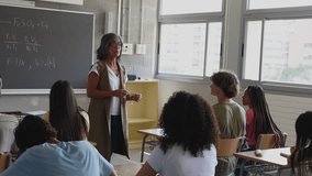 Senior female teacher explaining lesson to attentive multi-ethnic students in classroom at high school. Education lifestyle concept - Powered by Shutterstock - Get 15% off with code: PIKWIZARD15