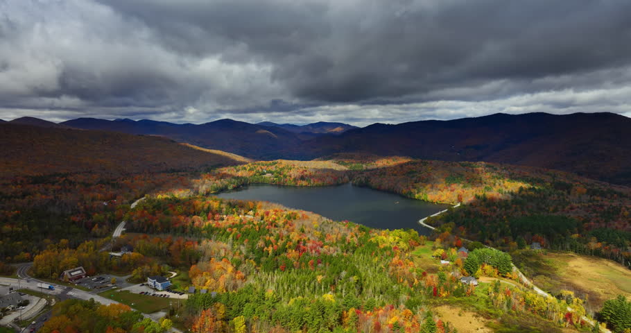 Mountain lake reflecting the grey cloudscape hanging above it. Vermont, New England, USA in autumn season. Aerial view.