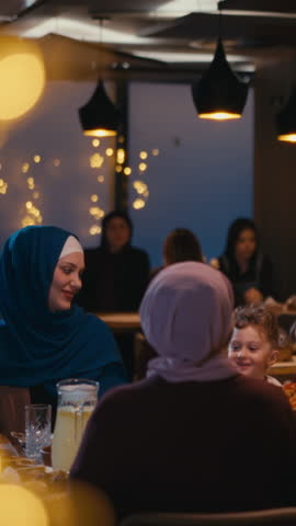 Vertical Screen: Warm and cozy gathering of Muslim women and children at a restaurant, sharing laughter and enjoying a meal. Concept of family bonding, togetherness, and Islamic cultural traditions