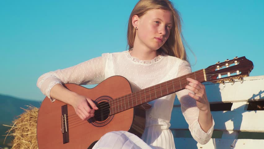 Girl playing Guitar. Romantic woman with a guitar. Beautiful singer outdoors. Talented guitarist. Sensual musician. Tender blonde woman with a guitar. Artistic woman playing music. Female guitarist.
