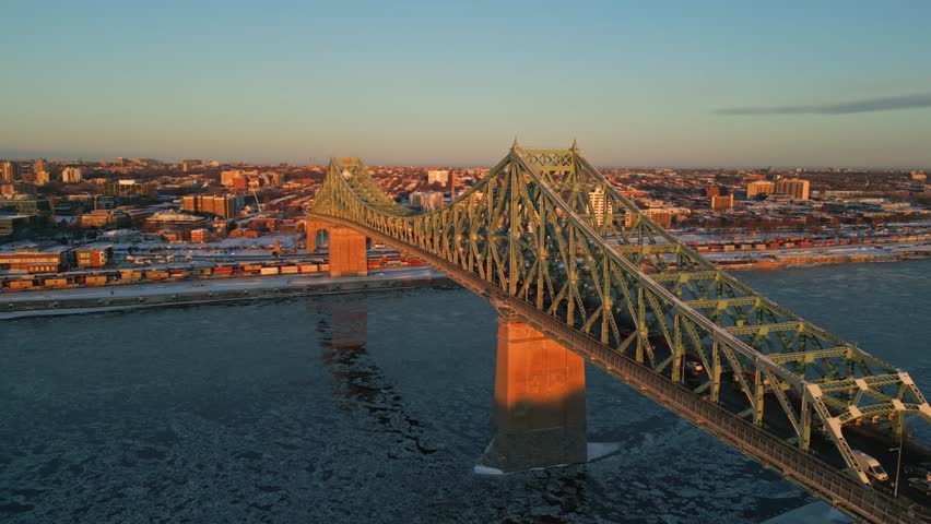 An elevated aerial view of Montreal’s steel bridge spanning across the frozen St. Lawrence River, North America, Quebec, Montreal, Canada.