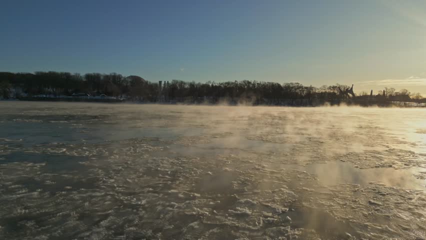 A tranquil icy winter morning scene featuring a foggy sunrise over the frozen lake, North America, Quebec, Montreal, Canada.