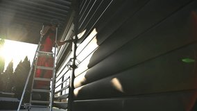 Man Checking on Carport Wall While Standing on Ladder in Evening Light. Modern Aluminium Pergola - Powered by Shutterstock - Get 15% off with code: PIKWIZARD15