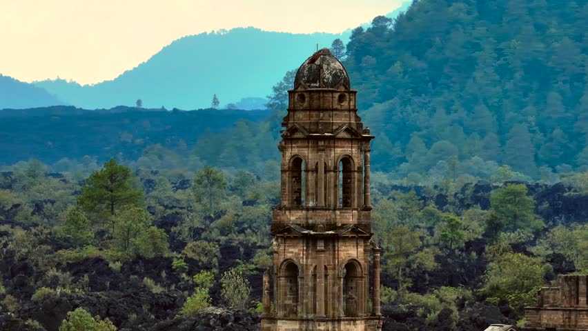 Close-up aerial view of the bell tower at the ruins of San Juan Parangaricutiro, surrounded by lava fields and resilient natural regrowth in Michoacán, Mexico