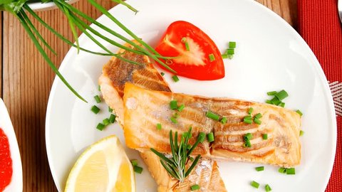 healthy sea food : roasted pink salmon fillet with vegetable salad chives lemon red caviar in white bowl with pepper in grinder and cutlery on white dish over wooden table
