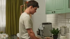 Young man in the morning at the kitchen at home preparing healthy breakfast, making fresh smoothie, cutting kiwis and puts in blender. - Powered by Shutterstock - Get 15% off with code: PIKWIZARD15
