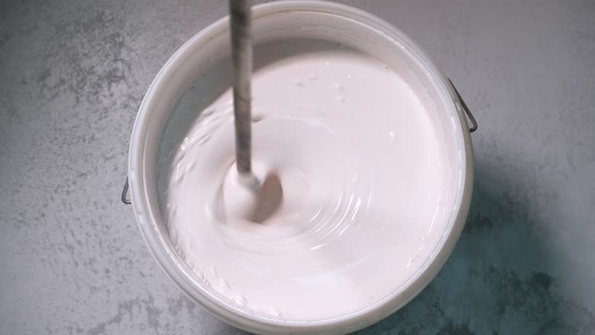 Mixing white paint in a bucket. Top view