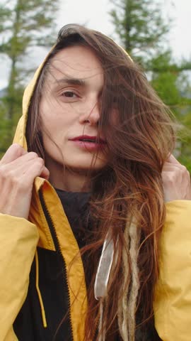 Portrait of a young woman with dreadlocks wearing a yellow and black jacket, Female look at camera. Girl hair is blowing in the wind, creating a sense of freedom and connection with nature