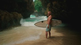 Sporty old man holds a surfboard on tropical island beach. Healthy senior man surfs in Bali, Uluwatu, make surfing. Elderly retired people enjoy outdoor active lifestyle water sport. Adult man surfs. - Powered by Shutterstock - Get 15% off with code: PIKWIZARD15