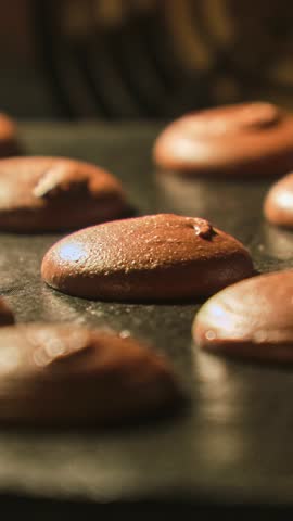 Macaron cookies in oven. Process of cooking chocolate macaroons. Timelapse of growing macarons. Baking concept. French sweets. Macarons baking. Vertical video. Close-up in 4K, UHD