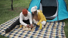 Interracial couple preparing food near tent during camping trip - Powered by Shutterstock - Get 15% off with code: PIKWIZARD15