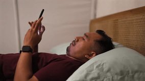 Asian man Using Smartphone in Bed at Night. Smiling guy Browsing Social Media, Romantic Chat, Dating Apps concept - Powered by Shutterstock - Get 15% off with code: PIKWIZARD15