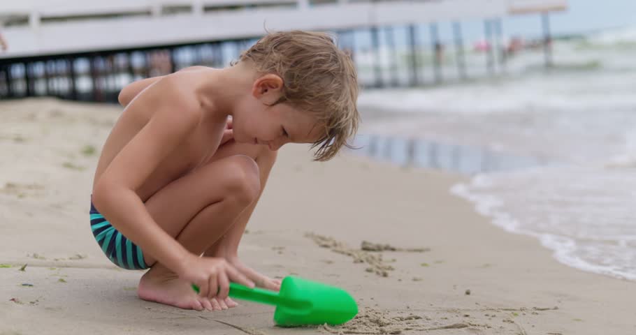 Young boy playing with shovel on beach