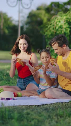Family enjoys an outdoor picnic in a park on a sunny day while sharing delicious food and laughter