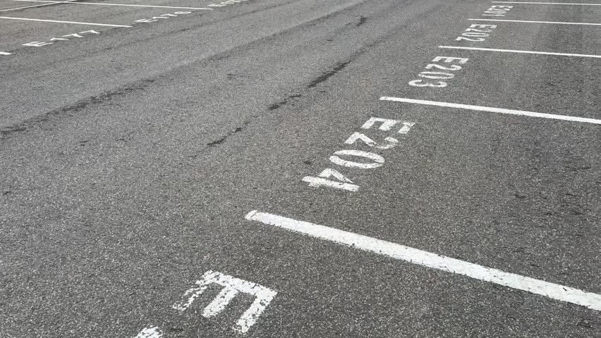 A wide and spacious view of an empty parking lot featuring marked parking spaces E204 and E205 clearly visible