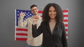 A smiling woman and a background man, both raising fists in a sign of solidarity or protest, in an indoor office setting featuring an american flag. - Powered by Shutterstock - Get 15% off with code: PIKWIZARD15