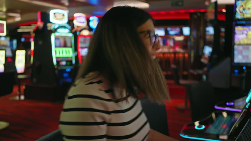 A joyful woman plays a slot machine in a lively casino, exuding excitement and entertainment.