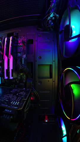 Vertical video. A smooth slider shot inside a gaming PC, highlighting vibrant RGB lighting, cooling fans, and hardware components. The camera movement emphasizes the detailed and glowing setup, creati