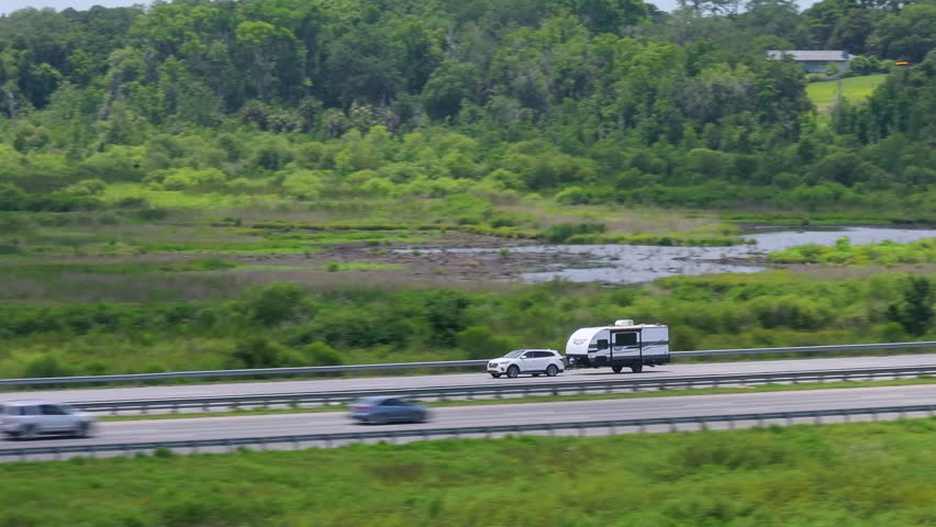 RV camper trailer towed by pick-up truck driving on American freeway at high speed. USA travel transportation infrastructure.