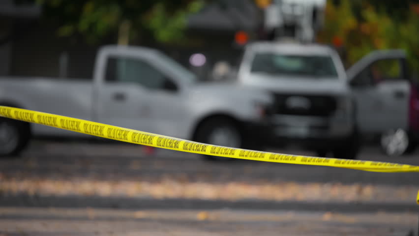 A bright yellow Crime Scene Do Not Cross tape stretched across an urban environment. Car accident