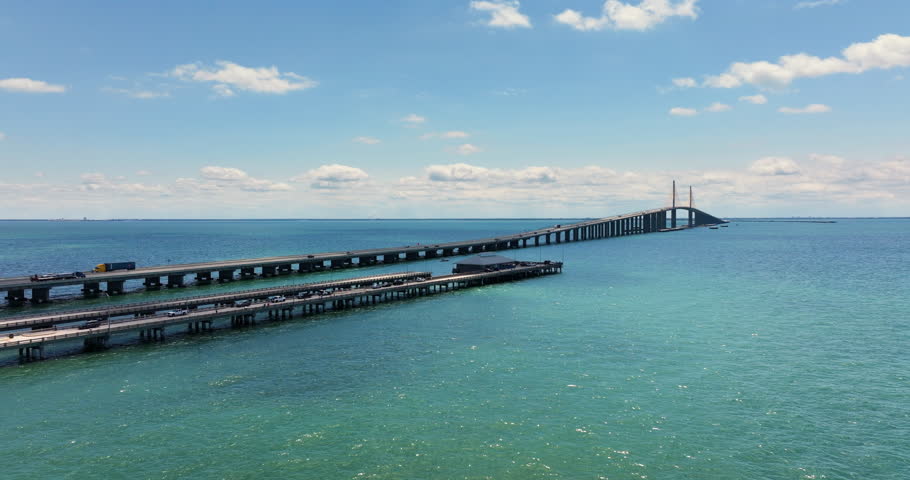 Sunshine Skyway Bridge with fishing pier in Florida, USA. Driving traffic over Tampa Bay