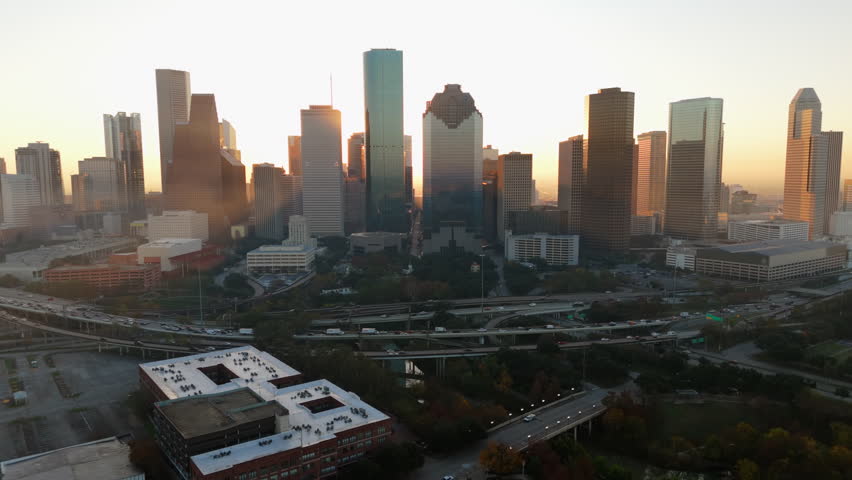 Stunning aerial drone shot beautifully captures Downtown Houstons breathtaking skyline during the early morning sunrise, showcasing majestic skyscrapers alongside the vibrant city life below