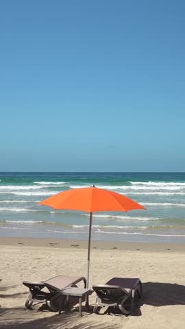 Vertical shot of the beach with sun loungers and orange parasol. Vacation in the all inclusive resort on the Caribbean sea