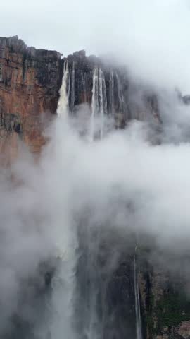 Angel Falls waterfall through the clouds. A huge flow of water falls from the mountain. The tallest uninterrupted waterfall in the world. Canaima National Park, Venezuela