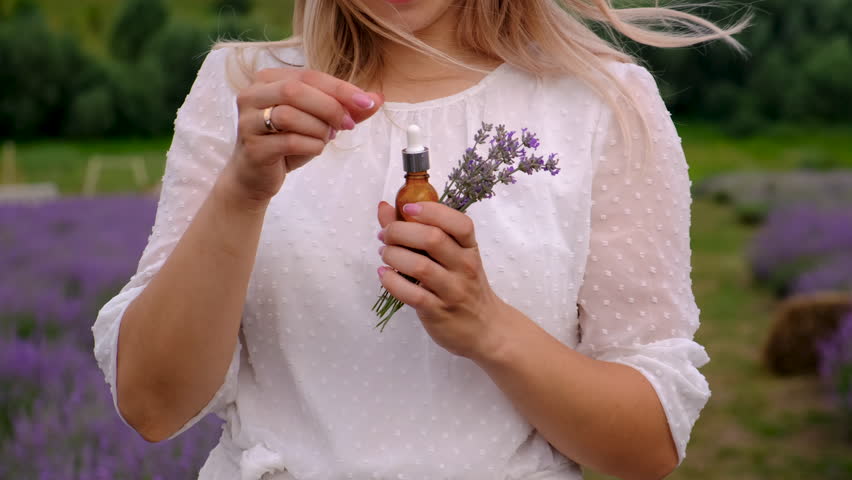 Woman with essential oil in lavender field. Selective focus.