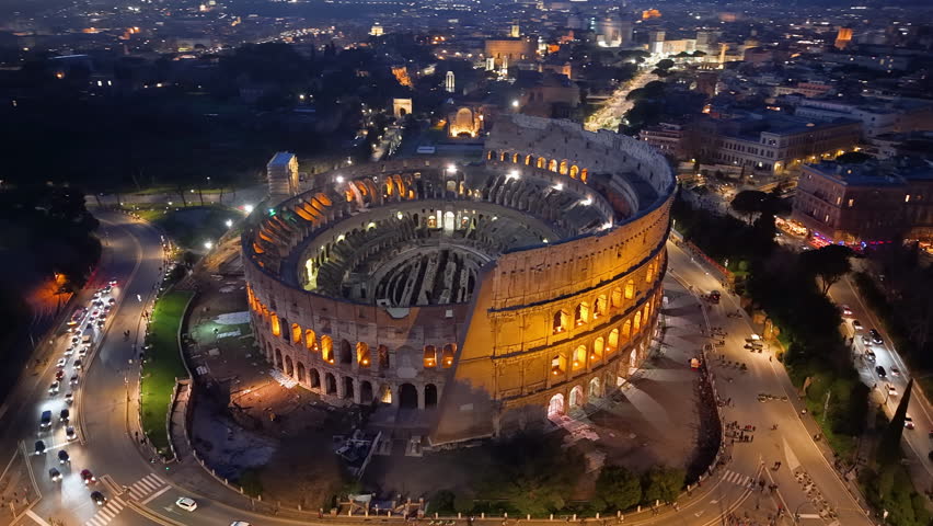 4k Aerial View of Beautiful sunset over the illuminated Colosseum in Roma with a vibrant skyline and city lights. Italy