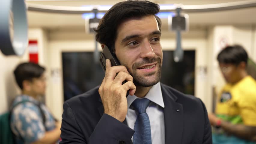 Smart business man phone calling to project manager while standing in train. Professional male leader talking to investor about marketing plan by using phone with blurring background. Exultant.