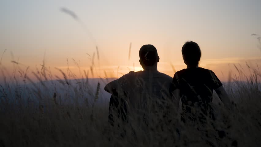 Back view of woman leaning on boyfriend at sunset