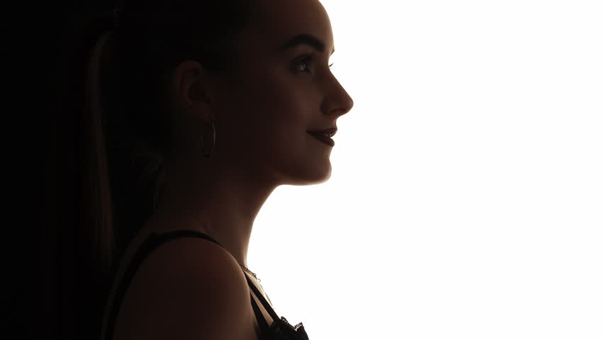 Female silhouette. Face contouring. Beauty enhancement. Dark contrast profile outline of confident woman smiling isolated on white copy space background.