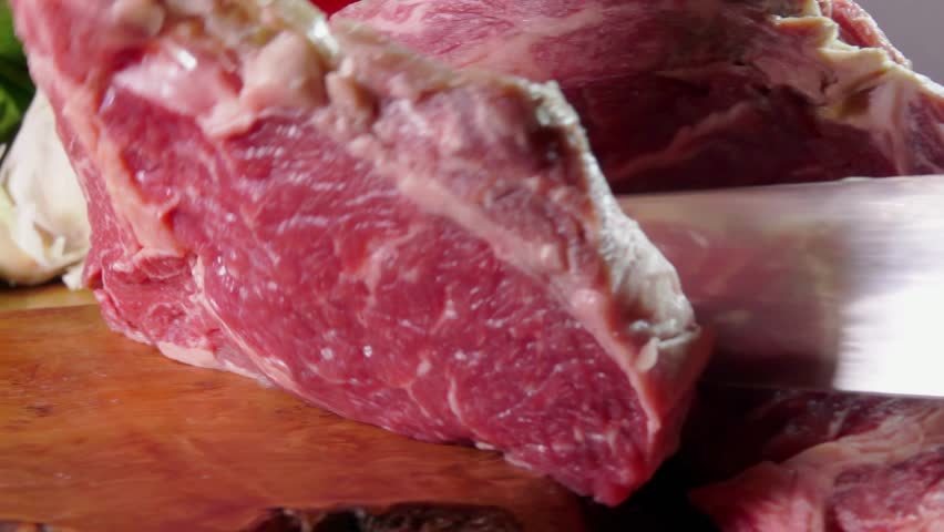 Knife cuts marbled beef steak on a wooden board slow motion. close-up. High quality 4k footage