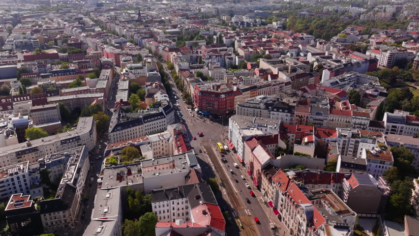Aerial views capture the Berlin skyline on a bright day, highlighting landmarks and vibrant green trees, creating a lively urban landscape