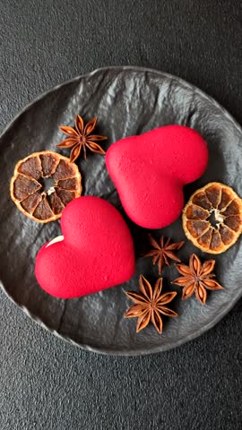 Red macaroons in the shape of a heart, sweets for the holiday of Valentine's Day on a dark concrete background