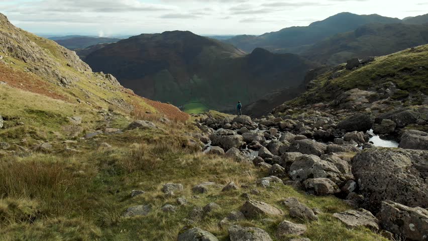 Aerial footage of female tourist enjoying the Lake District landscape. Glacial ribbon lakes and rugged mountains, Cumbria, North West England, UK.