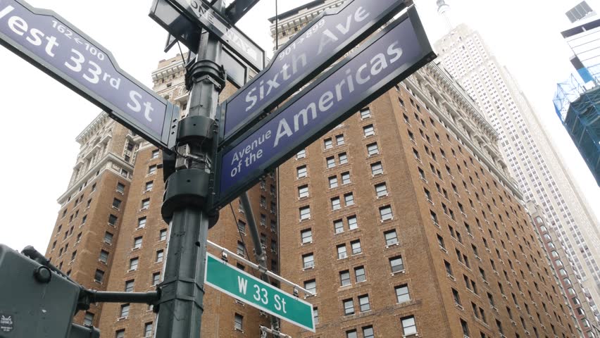 New York City crossroad, street intersection road sign on post. Empire State building, Midtown district, Americas 6th avenue, NYC, United States. Highrise skyscraper architecture, corner text roadsign
