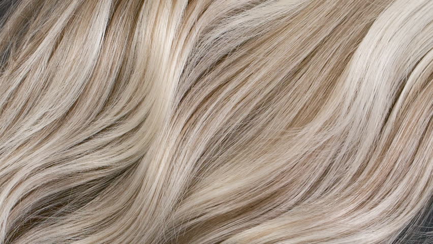 Closeup blond hair texture, slow motion of female hand combing long curly hair