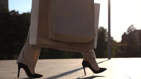 Feet of female customer in high heel shoes walking at sidewalk after purchases with shopping bags . Fashionable woman carries paper packets going along urban street. Concept of leisure and free time - Powered by Shutterstock - Get 15% off with code: PIKWIZARD15