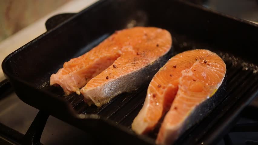 Cooking fresh salmon fillets in a cast iron skillet on the stove for a delicious and healthy meal