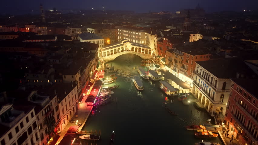 Aerial view of Venice, Italy featuring the famous Rialto Bridge and gondolas traveling through the Grand Canal