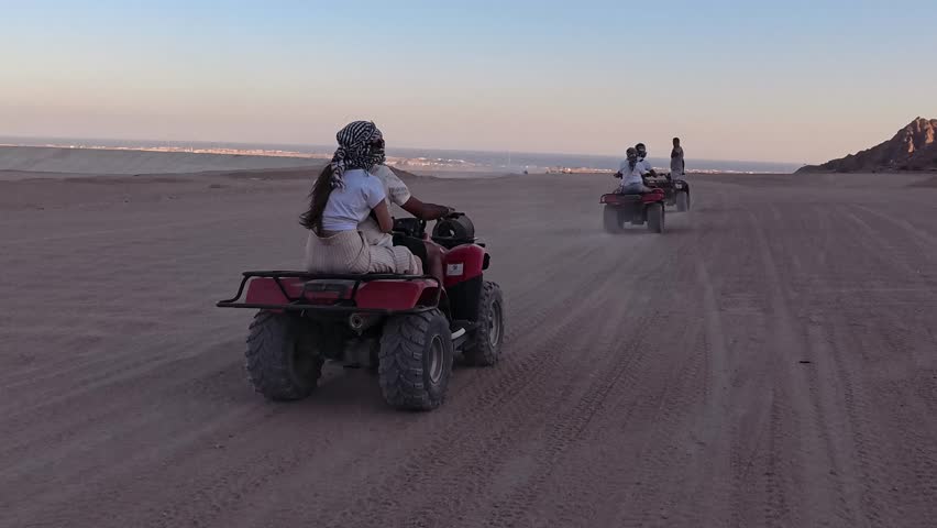 Quad bike ride through the desert near Sharm el Sheikh, Egypt.Adventures of desert off-road on ATV.Sand and Sand Borkhan. Rock and sunset. Quad Cycle Travel. Excursion with people.
