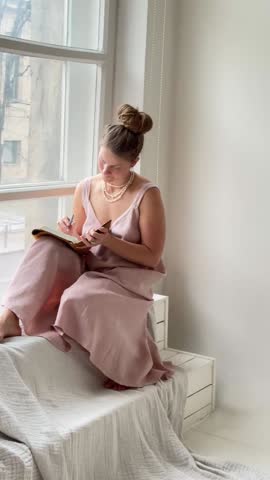 Young attractive thoughtful woman writing notes in her study notebook. Student in the process of studying. Woman studying.