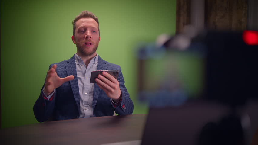 Male youtuber influencer recording a video for social media in green screen studio talking into the camera