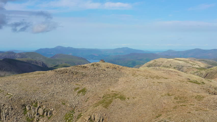 Aerial drone orbit of Scafell Pike summit, the highest peak in England, captured on a clear, sunny summer day.